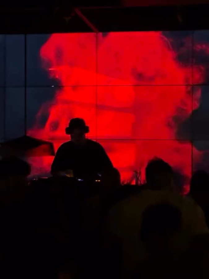 DJ set in front of a red LED video wall