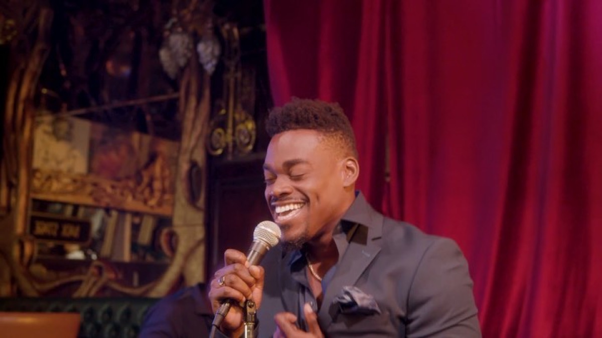 Still from the Stay music video — singer in front of a red curtain